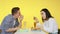 A guy and a girl on a date eat fast food and drink drinks from glasses on a yellow background. Date. The concept of