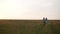 A guy with a girl embracing goes along a country road to the field. Sunset, Summer.