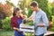 Guy and girl gardeners hold the white wooden box in hands and put there pots with seedlings on a sunny day in the