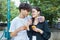 Guy and a girl are holding burgers and drinks in their hands. the girl gives the guy a drink from her glass