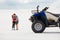 The guy and the girl are kissing in the desert, their quad bike stands next to them, having fun and enjoying, a couple in love