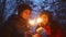 A guy and a girl light sparklers in the winter forest for Christmas.