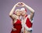 Guy and girl in love in Santa costumes folded their hands in the shape of a heart. Christmas and New year concept