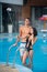 Guy and girl posing against the swimming pool with perfect aqua water and taking selfie photo with monopod on the resort