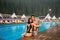 Guy and girl posing against the swimming pool with perfect aqua water and taking selfie photo with monopod on the resort