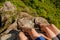 Guy and a girl in sneakers sit on a rocky mountain, dangling their legs down