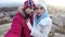 A guy and a girl stand on the edge of a rock in an embrace in winter and kiss joy appears on their faces