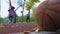 A guy and a girl throw a basketball in a basket on a playground.