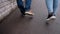 A guy with a girl walking on the wet asphalt after the rain. Close-up of their feet walking on the sidewalk.