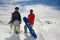 Guy and a girl in warm clothes stand with snowboards against the mountain snow tops