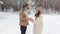 A guy gives a girl a gift in a snowy winter forest a happy girl jumps for joy and hugs a man