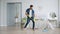 Guy in gloves mopping floor in apartment and dancing with plastic mop