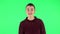 Guy goes and dances, smiles and rejoices on a green screen.Profile side view