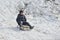 The guy goes down on a sled on a snowy hill in winter