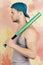 Guy in grey tank top holds bright green bat on shoulder. Sports and game concept. Player with serious or tired face