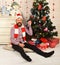 Guy in hat and scarf on floor by Christmas tree