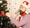 Guy in hat and scarf stands by fir tree