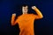 A guy with headphones is dancing to the music. A cheerful man in an orange T-shirt dances to his favorite music
