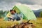 Guy with his girlfriend sits near tent. Majestic Carpathian Mountains. Beautiful landscape of untouched nature