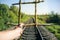 Guy is holding prisons grate made from wooden sticks. Freedom concept photo with rail tracks in the green field. Railway transport