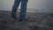 Guy legs in fashionable sneakers walking on beach. Man feet exploring sea coast