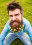 Guy with lesser celandine flowers in beard taking selfie photo. Hipster with angry grimace on face taking selfie photo