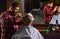 Guy with long dyed blond hair close up rear view. Cut hair. Barber making hairstyle for bearded man barbershop