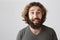 Guy is looking at tasty food on festival. Portrait of handsome funny eastern male with beard and long curly hair