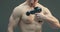 Guy massaging chest muscles by handheld deep tissue percussion massage gun for warm-up and recovery, close up