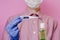 A guy in a medical glove holds a bottle of antiseptic sanitizer and a thermometer. Pink background. Antibacterial effect