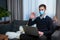 Guy medical mask couch with laptop communicates via online video communication