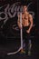 A guy, with a naked bare chest, stands and holds on shoulder a heavy long rope. Indoors in the gym.