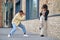 Guy photographing girl in strike pose near brick building