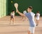 Guy playing pelota at open-air fronton, swinging wooden bat to return ball