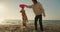 The guy plays with a red toy with his light-colored dog on a sunny beach in the morning