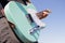 The guy plays a turquoise electric guitar against a cloudless blue sky