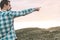 Guy pointing to the horizon in the mountain in casual dress