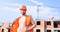 Guy protective helmet stand in front of building made out of red bricks. Builder orange vest helmet work construction