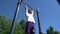 Guy pulls up on the bar on a Sunny day, shooting from a lower angle