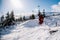 A guy in a red jumpsuit jumps on a snowboard from a snow ledge