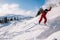 A guy in a red jumpsuit jumps on a snowboard from a snow ledge