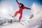 A guy in a red jumpsuit jumps on a snowboard from a snow ledge