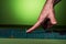 The guy `s hand touch on a green massage mat in twisted form on a green background. Advertising and subject shooting. For