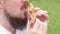 The guy\\\'s mouth bites a big burger close-up. Snack in nature