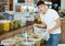 Guy scooping pickled olives in the produce section of supermarket