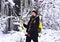 Guy with serious face with forest covered by snow.