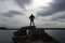 Guy Silhouetted in a Super Hero Pose on a Rock Jetty