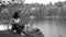 Guy sits on high bank above lake. Relax in nature.