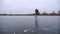 Guy skating on frozen river at cloudy day. Young man shod in figure skates sliding on ice surface outdoor. Sportsman