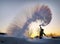 Guy splashes boiled water from a thermos over his head against the backdrop of a sunset in frosty weather. The effect of instant